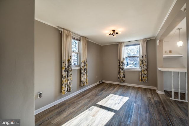 unfurnished room featuring baseboards, wood finished floors, and crown molding