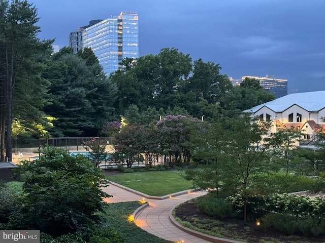 view of community featuring a view of city, a yard, and fence