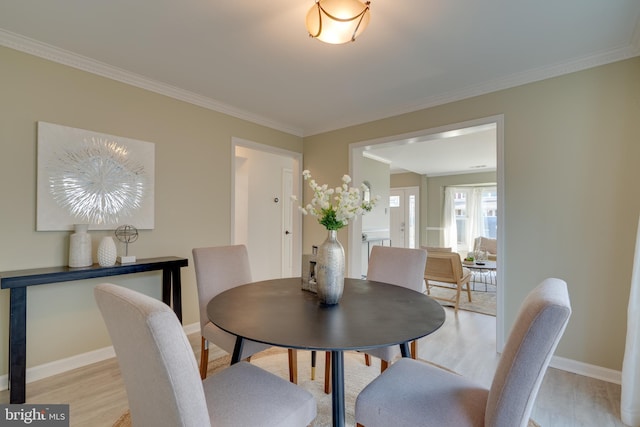 dining room featuring baseboards, crown molding, and light wood-style floors