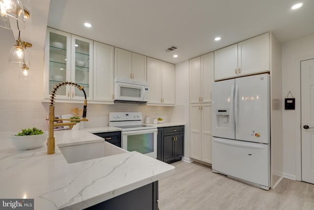 kitchen with visible vents, light stone counters, white appliances, light wood-style floors, and white cabinets