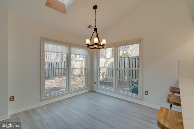 unfurnished dining area featuring a chandelier, wood finished floors, visible vents, and a skylight