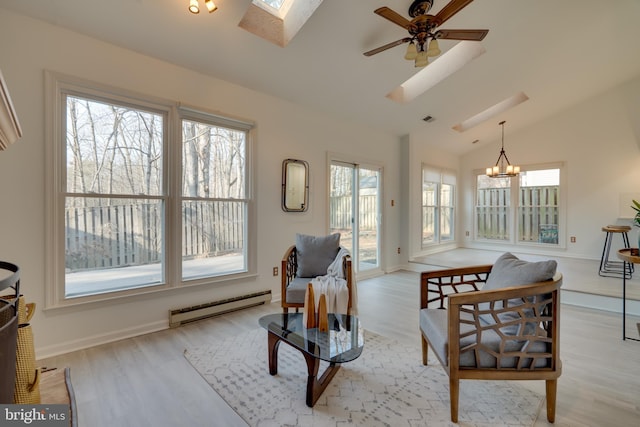 living area with lofted ceiling with skylight, baseboard heating, ceiling fan with notable chandelier, and light wood finished floors