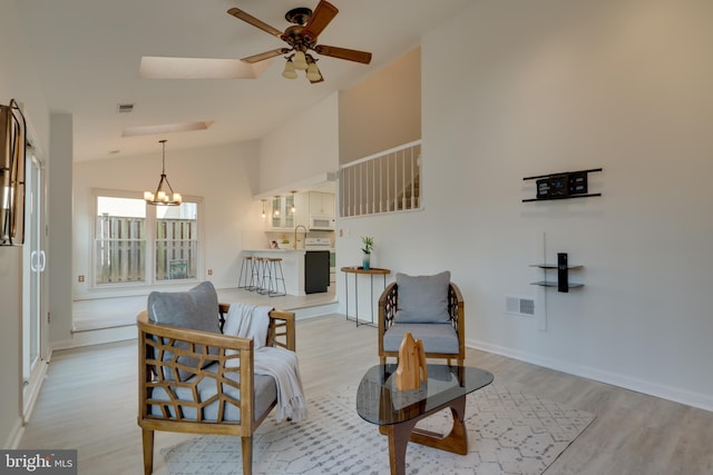 living area featuring ceiling fan with notable chandelier, visible vents, and light wood-type flooring