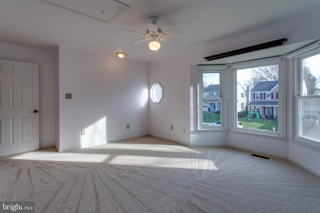 empty room with a wealth of natural light, visible vents, attic access, and carpet floors