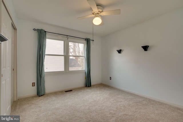 empty room with a ceiling fan, visible vents, carpet floors, and baseboards