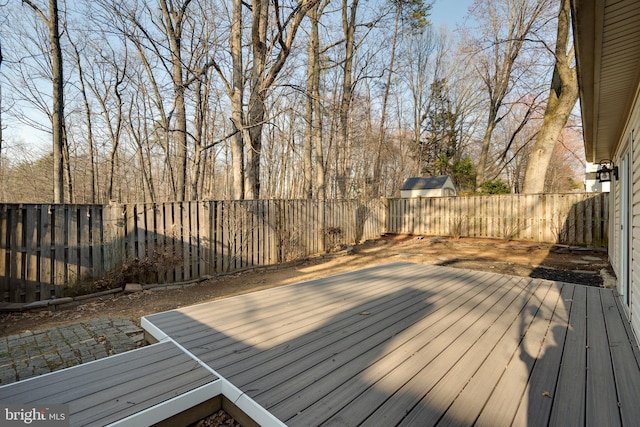 wooden terrace featuring a patio, an outbuilding, and a fenced backyard