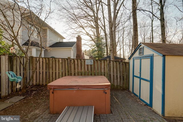 exterior space featuring an outbuilding, a storage unit, a fenced backyard, and a hot tub