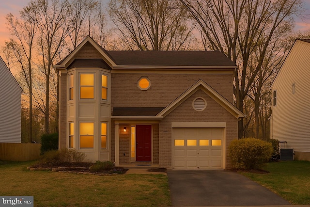 view of front facade featuring brick siding, a yard, and aphalt driveway