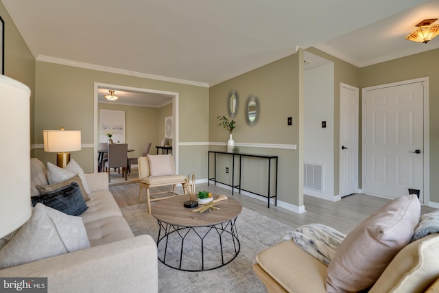 living area featuring visible vents, baseboards, wood finished floors, and crown molding