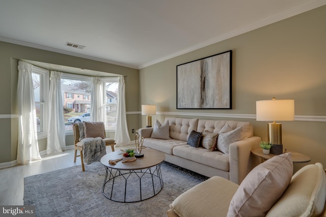 living area featuring visible vents, baseboards, wood finished floors, and ornamental molding