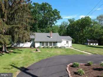 single story home featuring driveway, a chimney, and a front lawn