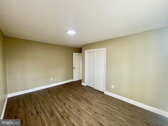 unfurnished bedroom with wood finished floors, baseboards, and a closet