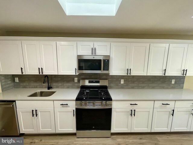 kitchen featuring white cabinets, appliances with stainless steel finishes, light countertops, and a sink