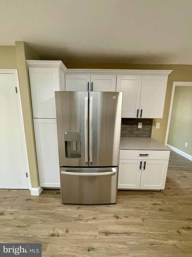 kitchen with light wood finished floors, stainless steel fridge, and white cabinetry