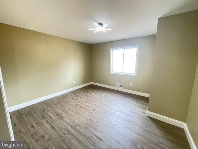 unfurnished room featuring visible vents, baseboards, and dark wood-style flooring