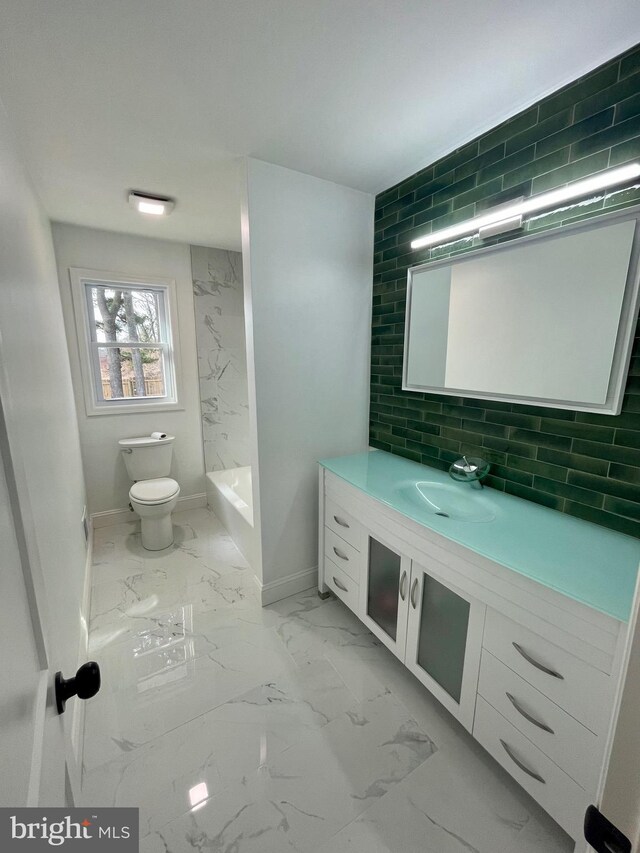 full bath featuring vanity, baseboards, toilet, marble finish floor, and backsplash