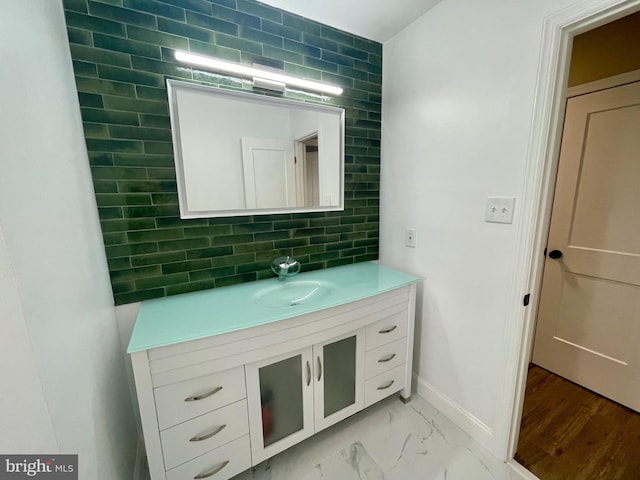 bathroom with decorative backsplash, marble finish floor, vanity, and baseboards