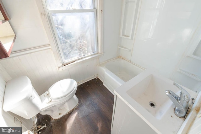 bathroom with toilet, a sink, a bathing tub, wood finished floors, and a shower