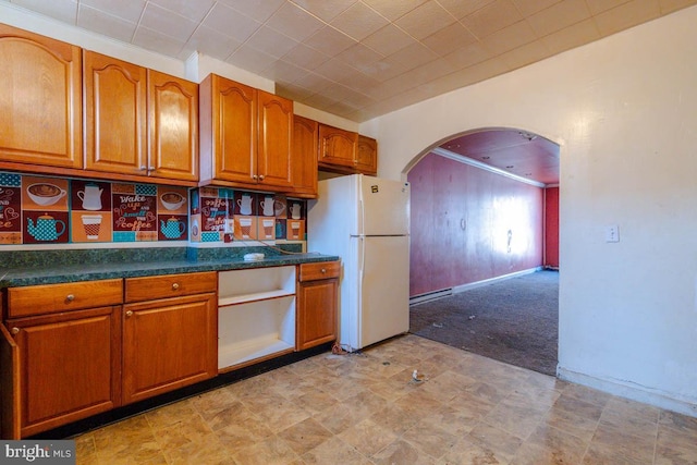 kitchen with dark countertops, brown cabinetry, and freestanding refrigerator