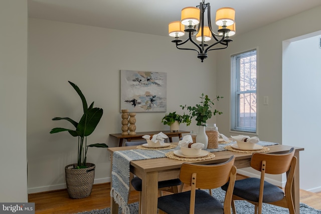 dining space featuring an inviting chandelier, wood finished floors, and baseboards