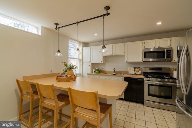 kitchen with a sink, appliances with stainless steel finishes, white cabinets, and a breakfast bar