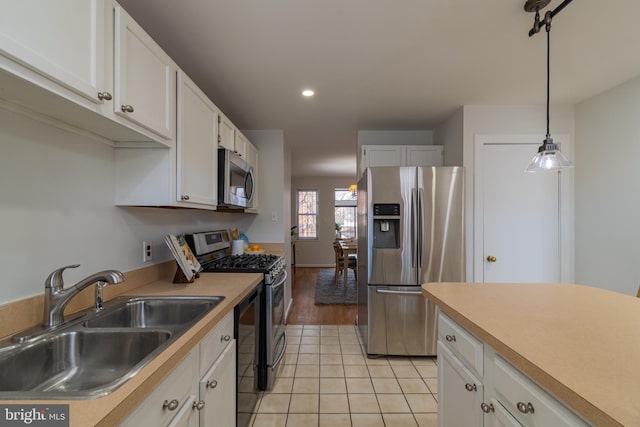 kitchen featuring white cabinets, stainless steel appliances, light countertops, and a sink