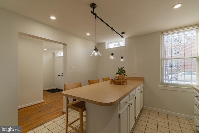 kitchen featuring recessed lighting, a peninsula, white cabinetry, and light countertops