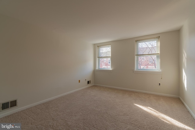 carpeted empty room featuring visible vents and baseboards