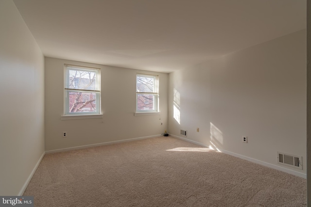 spare room with visible vents, baseboards, and light colored carpet