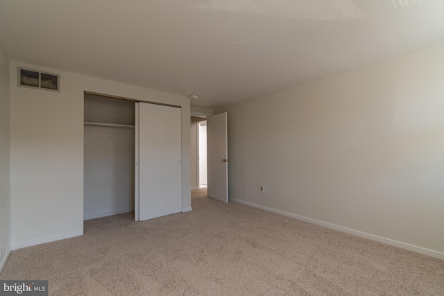 unfurnished bedroom with light carpet, visible vents, baseboards, and a closet