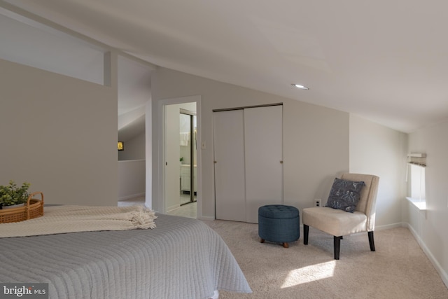 bedroom with vaulted ceiling, light colored carpet, a closet, and baseboards