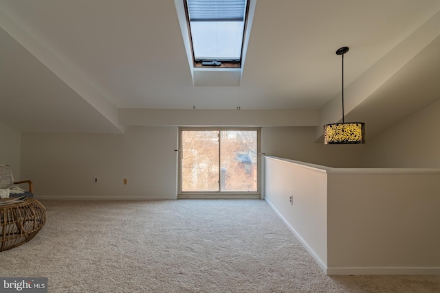 carpeted empty room with a skylight and baseboards