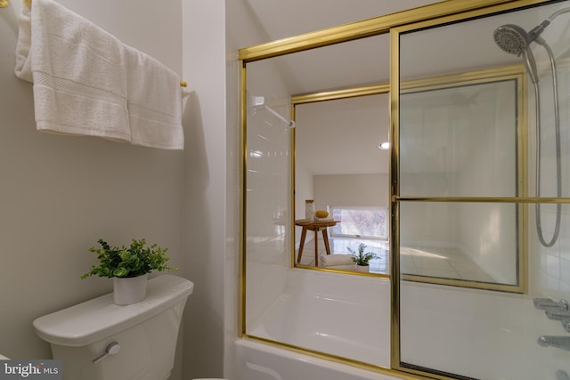 bathroom featuring bath / shower combo with glass door and toilet