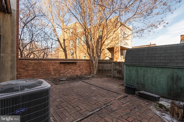 view of patio with a storage shed, an outbuilding, central AC unit, and a fenced backyard