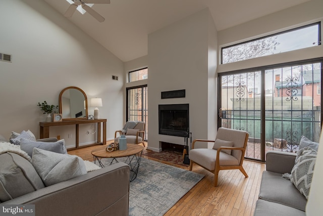 living area featuring visible vents, high vaulted ceiling, ceiling fan, and hardwood / wood-style flooring