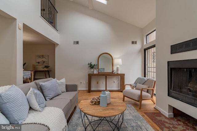 living area with visible vents, a fireplace, baseboards, and wood finished floors