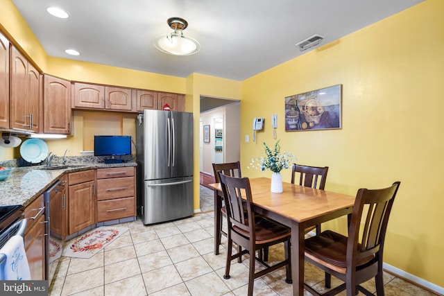 kitchen featuring visible vents, a sink, stone countertops, stainless steel appliances, and light tile patterned flooring