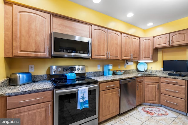 kitchen featuring appliances with stainless steel finishes, stone countertops, and a sink