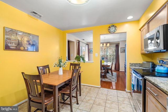 dining room featuring a notable chandelier, light tile patterned floors, baseboards, and visible vents