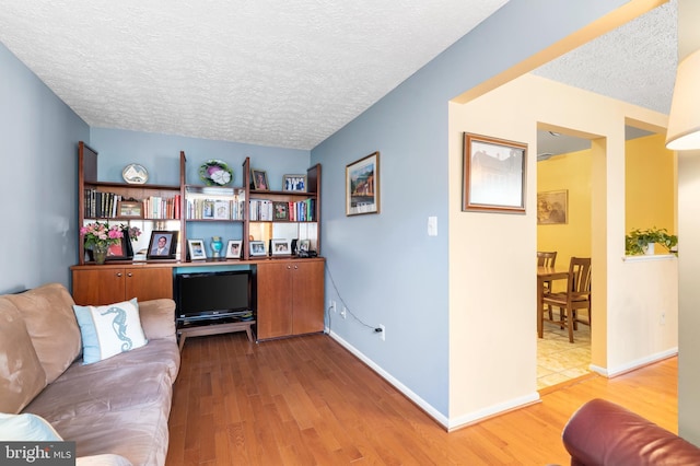 home office with baseboards, light wood-style floors, and a textured ceiling