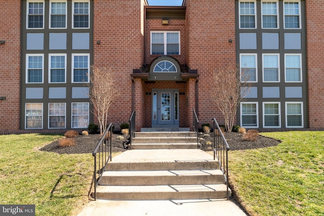 property entrance featuring brick siding and a yard