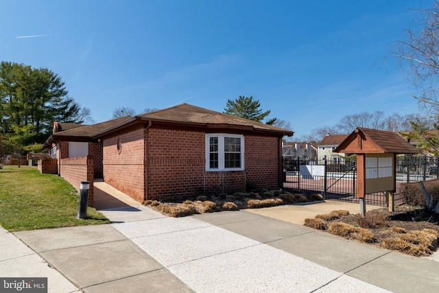 view of side of property featuring brick siding, a lawn, and fence