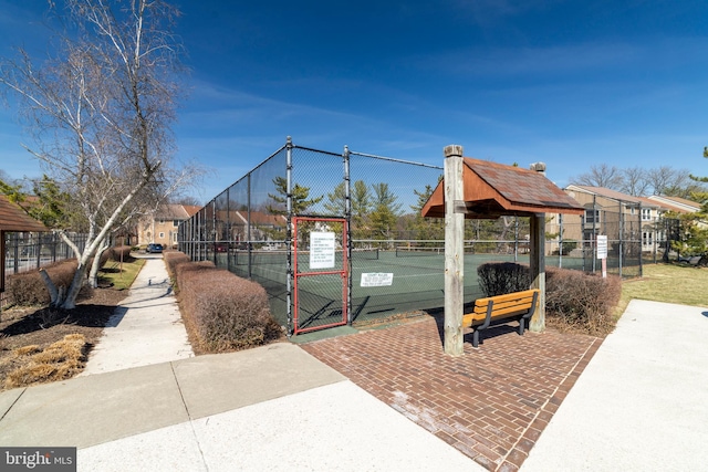 view of home's community with a tennis court, a gate, and fence