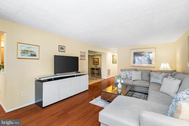 living room featuring baseboards, a textured ceiling, and wood finished floors