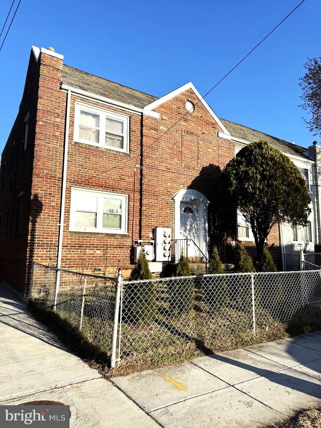 view of front of property with a fenced front yard, a chimney, and brick siding