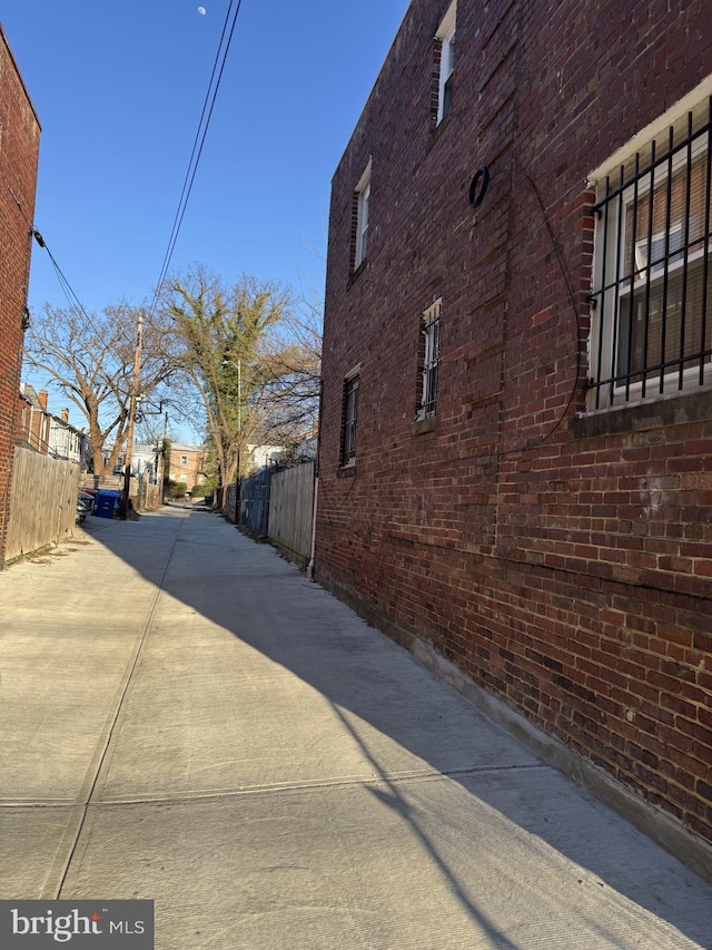 view of side of property with brick siding and fence