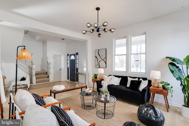 living area featuring a chandelier, stairway, light wood-style flooring, and baseboards