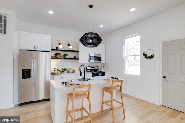 kitchen featuring light wood-style flooring, a sink, white cabinetry, stainless steel appliances, and light countertops