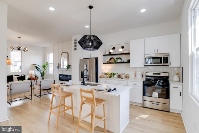 kitchen featuring light wood-style flooring, white cabinets, backsplash, and stainless steel appliances