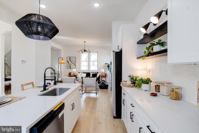 kitchen featuring open shelves, a sink, light countertops, appliances with stainless steel finishes, and tasteful backsplash